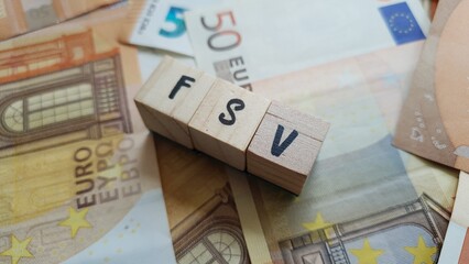 FSV acronym made of wooden letter cubes on pile of Euro banknotes. Fonds de Solidarité Vieillesse...
