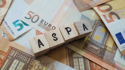 ASPA acronym made of wooden letter cubes on pile of Euro banknotes. Allocation de Solidarité aux...