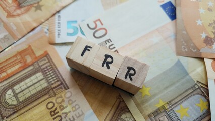 FRR acronym made of wooden letter cubes on pile of Euro banknotes. Fonds de Réserve pour les...