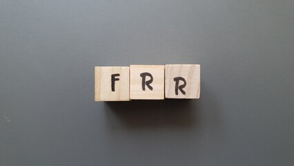 FRR acronym made of wooden letter cubes on dark background. Fonds de Réserve pour les Retraites...