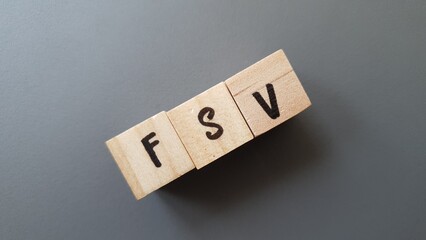 FSV acronym made of wooden letter cubes on dark background. Fonds de Solidarité Vieillesse...