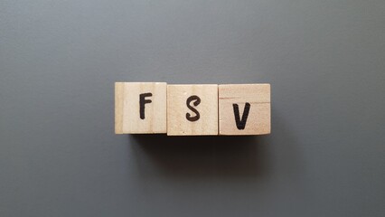 FSV acronym made of wooden letter cubes on dark background. Fonds de Solidarité Vieillesse...
