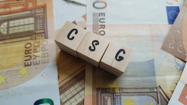 CSG acronym made of wooden letter cubes on pile of Euro banknotes. Contribution Sociale G&eacute;n&eacute;ralis&eacute;e (General Social Contribution, a tax funding social security)