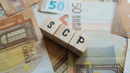 SCP acronym made of wooden letter cubes on pile of Euro banknotes. Société Civile de Placement...