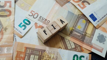 FIA acronym made of wooden letter cubes on pile of Euro banknotes. Fonds d’Investissement...