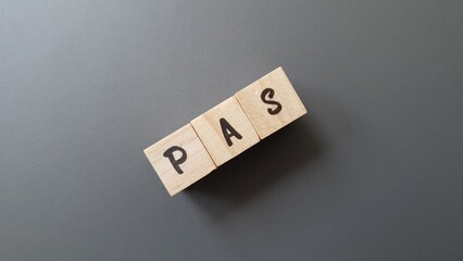 PAS acronym made of wooden letter cubes on dark background. Prélèvement à la Source (Withholding...