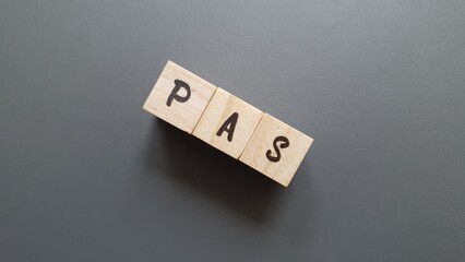 PAS acronym made of wooden letter cubes on dark background. Prélèvement à la Source (Withholding...