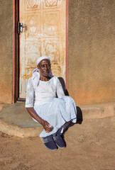 village single zezuru old african woman wearing a headscarf sited in front of the house , in the yard, close portrait