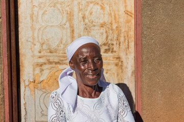 village single zezuru old african woman wearing a headscarf sited in front of the house , in the yard, close portrait