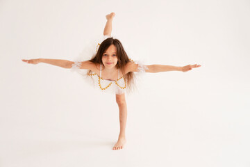 A ballerina girl dancing doing splits and stretching on white background in white tutu on white...