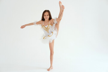 A ballerina girl dancing doing splits and stretching on white background in white tutu on white...
