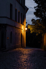 A peaceful and serene evening scene showcasing a charming cobblestone street warmly illuminated by an old lamp