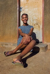 village single young african teenager with braids standing in front of the house , in the yard, close portrait