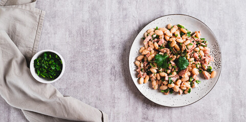 Protein tuna, beans, herb salad on a plate on the table top view web banner