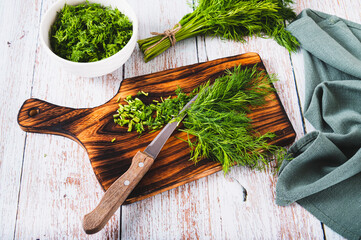 Chopped fresh dill and knife on cutting board on table