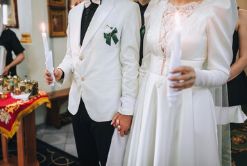 Photo of bride and groom in church with candles in hands during wedding ceremony ritual. Religious...