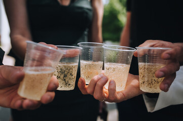 Many people at a party, wedding, celebration hold plastic glasses with champagne. Photography,...