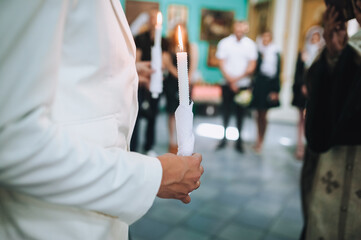 Photo of bride and groom in church holding candles during wedding ceremony. Religious concept.