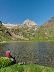 Hiker resting by a mountain lake in the pyrenees.