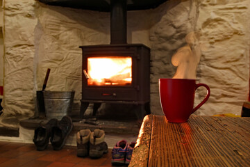 Warming up next to a log burner with a cup of tea after a cold winter hike