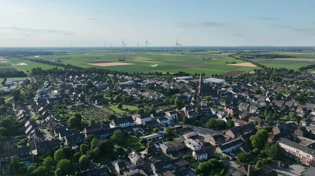 Luftbildaufnahme von Aldekerk bei Kerken mit Bahnhof an einem sonnigen Sommerabend. Weitwinkel-Drohnenflug &uuml;ber D&auml;cher, Felder und Gleisanlagen im warmen Licht der Abendsonne.