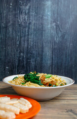 Indonesian street food culinary chicken noodles, noodles served with a mixture of sweet chicken pieces and fresh mustard greens with a thick broth