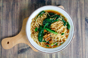 Indonesian street food culinary chicken noodles, noodles served with a mixture of sweet chicken pieces and fresh mustard greens with a thick broth