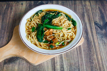 Indonesian street food culinary chicken noodles, noodles served with a mixture of sweet chicken pieces and fresh mustard greens with a thick broth