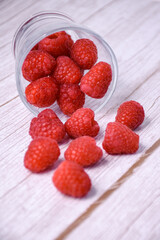 Fresh raspberries in a glass jar on a wooden background