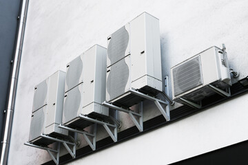 Industrial air conditioning units. HVAC system on building facade. Cooling technology on white wall. Ventilation equipment detail. Outdoor AC compressors. Modern infrastructure and engineering.