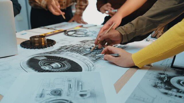 A group of engineers gathered around a workstation, discussing intricate mechanical designs displayed on blueprints, showcasing teamwork and innovation in a creative workspace. SACTR - Powered by Adobe