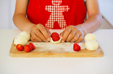 Homemade strawberry dumplings preparation with curd cheese dough on wooden board, traditional Czech sweet dish, known as jahodove knedliky or strawberry kn&ouml;del, typical in Central European cuisine
