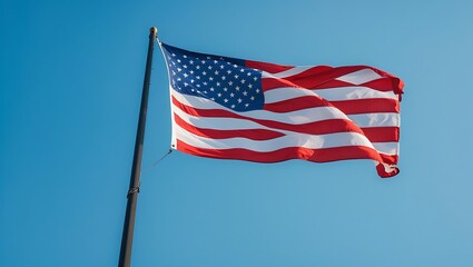 Obraz premium A vibrant American flag flutters in the breeze under a bright blue sky
