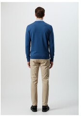 Obraz premium Rear view of a man wearing blue sweater and khaki pants standing against a bright white studio setting