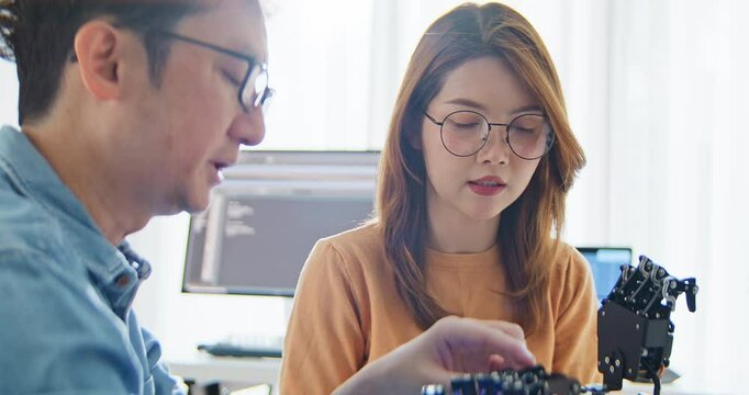 Asian male, female programming developer work together at home office, coding robotic arm machine. Information technology, software engineer programmer job, man woman coworker teamwork concept