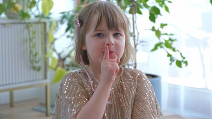 Adorable Happy Caucasian Preschooler Girl Making Shush Gesture Putting Index Finger on Her Lips and...