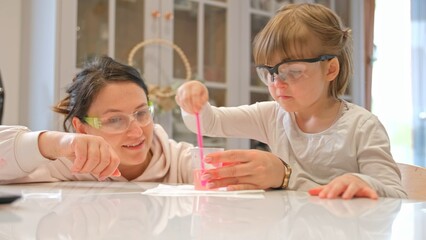Caucasian Woman and Preschooler Daughter Child Girl Wearing Protective Glasses Having Fun Preparing STEM Science Experiment on Kitchen Table using Education Kit for Homeshooling Learning