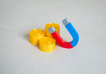 Stack of money coins and magnet. Concept of attraction of financial resources. Learn to earn money....