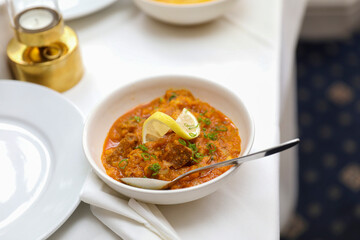 Delicious Indian Lamb Curry in a White Bowl with Lemon Garnish