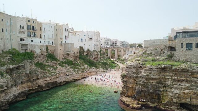 Aerial view of Lama Monachile beach in Polignano a Mare with turquoise sea, dramatic cliffs, and scenic views of the Adriatic coastline in Puglia.