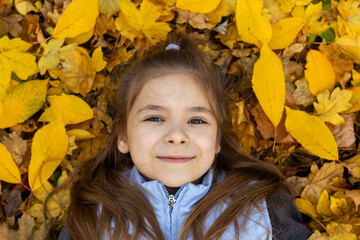 Smiling child surrounded by fall foliage enjoying the autumn season outdoors
