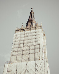 German Church Tower Surrounded by Scaffolding in Urban Setting