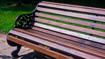 Horizontal photo of a large wooden park bench with metal details
