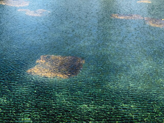 Gentle breeze stirs ripples across the water, casting long shadows across the gravel driveway.