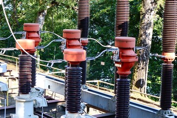  High-voltage insulators and electrical components of a power substation outdoors, surrounded by...
