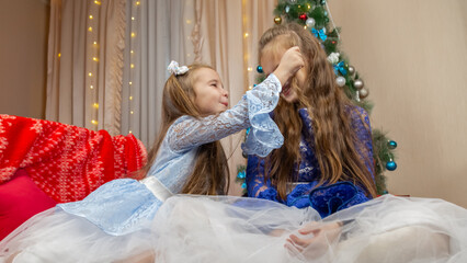 A happy little girls in a beautiful blue dress sitting in festive Christmas interior with a gifts...