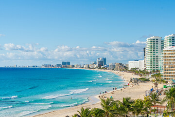 Panoramic view of Cancun’s Hotel Zone with golden sand, turquoise ocean, palm trees, and luxury resorts under a bright blue sky High-quality photo