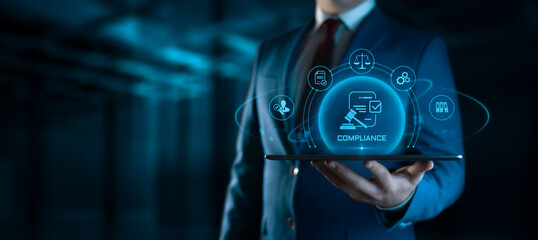 Businessman holding tablet with compliance icons on screen - business and regulations concept