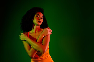 Elegant young woman embracing with closed eyes in gradient green background, showcasing beauty