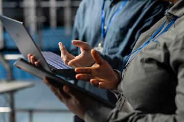 Server room coworkers doing brainstorming, backing up storage arrays using software on laptop. Team...